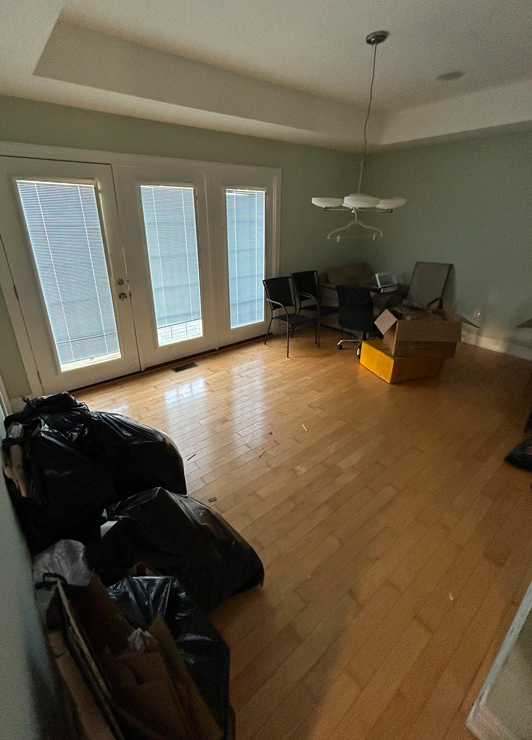 Empty room interior featuring polished hardwood floors and large glass doors leading outside.