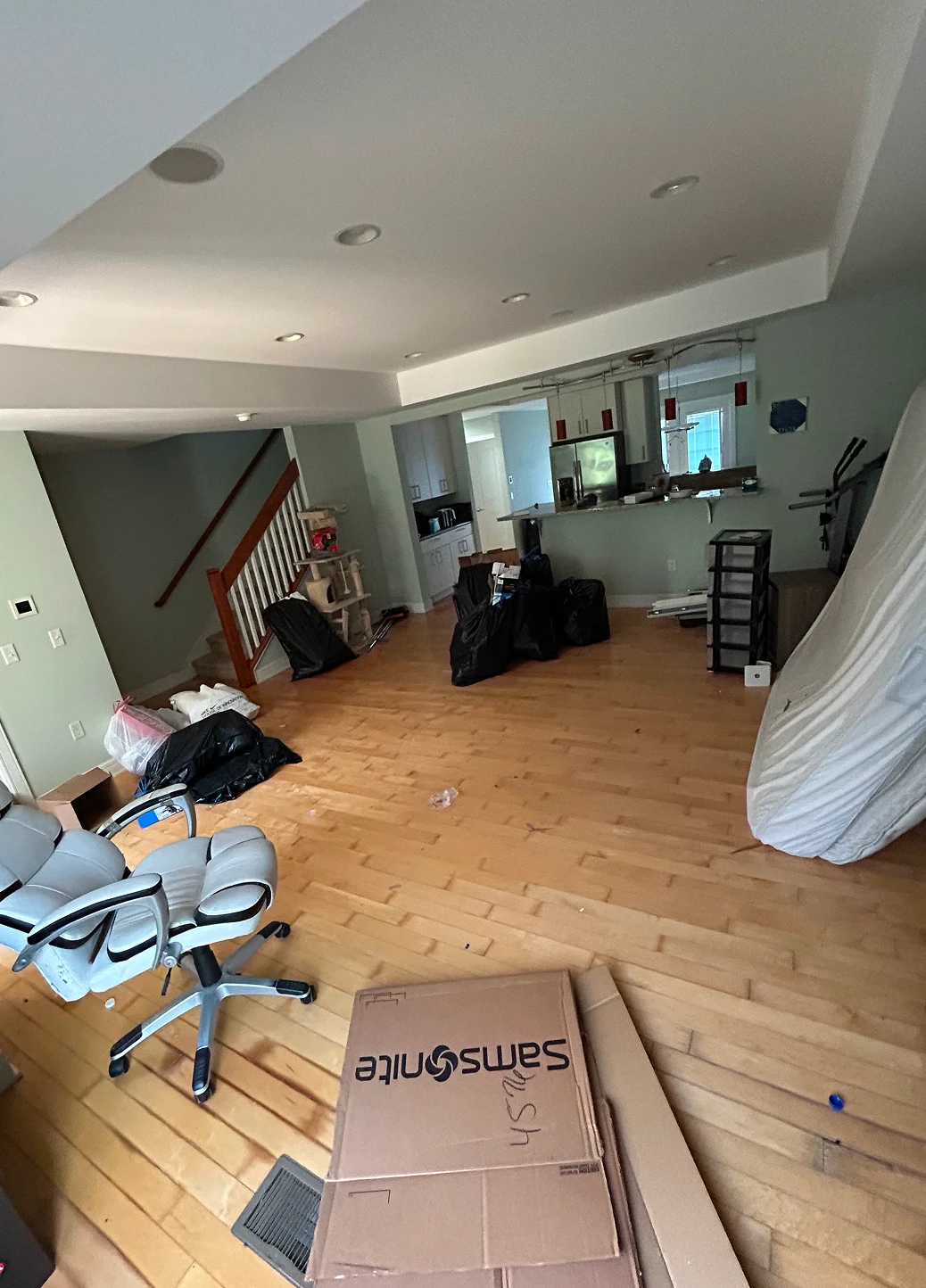 Interior shot of a room undergoing renovation or moving, with open floor space and items piled in the corner.